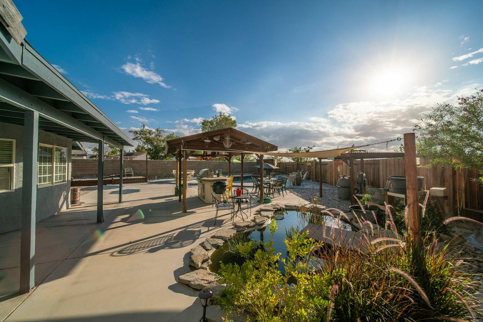 Finished backyard with a stone-edged pond, ornamental grasses and a shaded patio