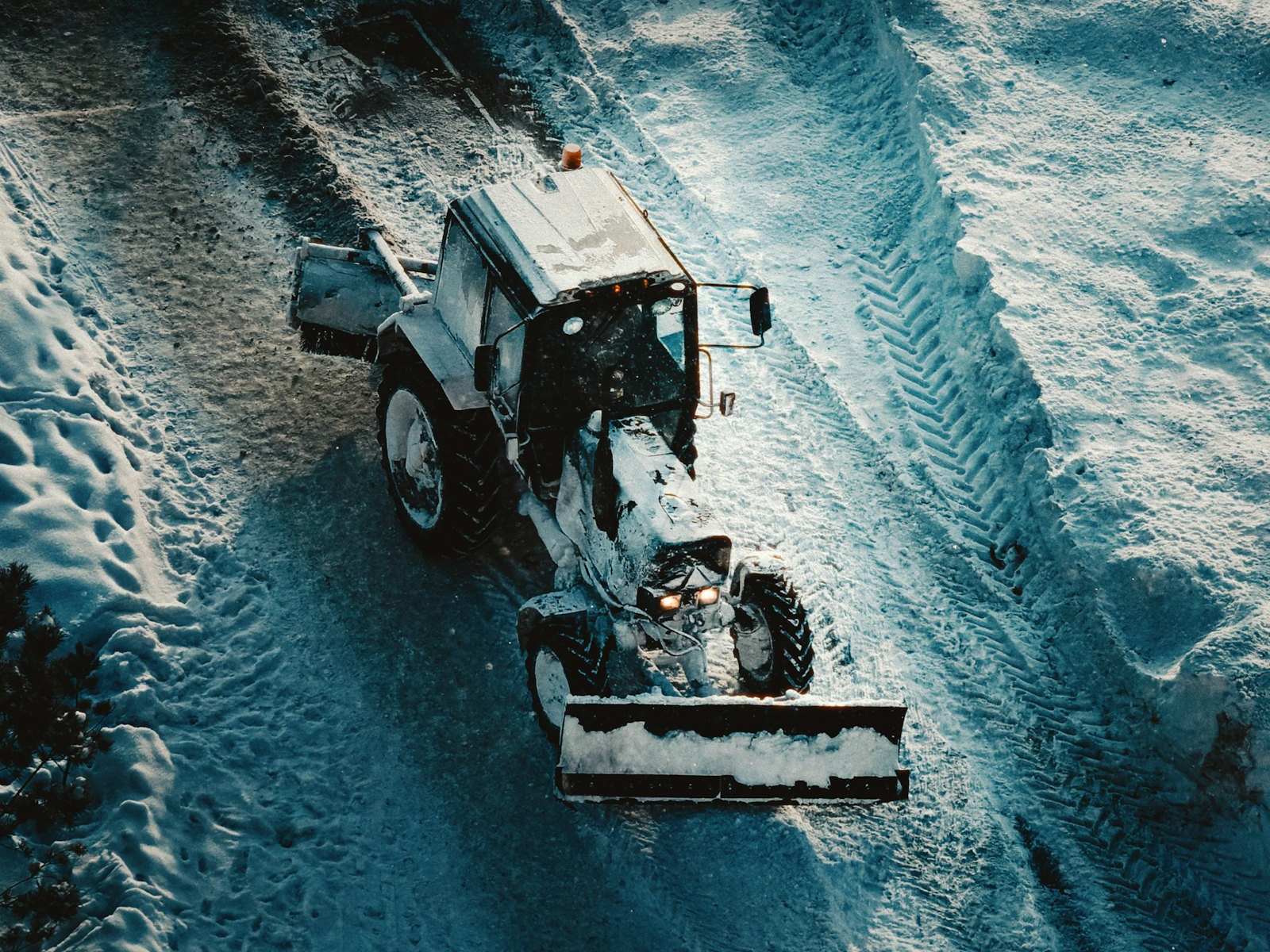 Overhead view of a small plow tractor clearing fresh snow