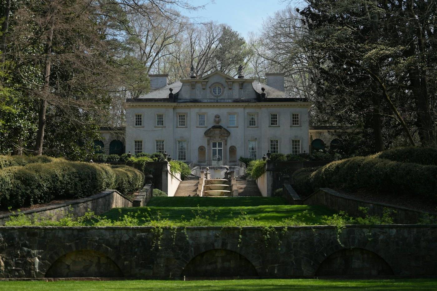 Large estate with terraced lawns, clipped hedges and stone steps leading to a grand house