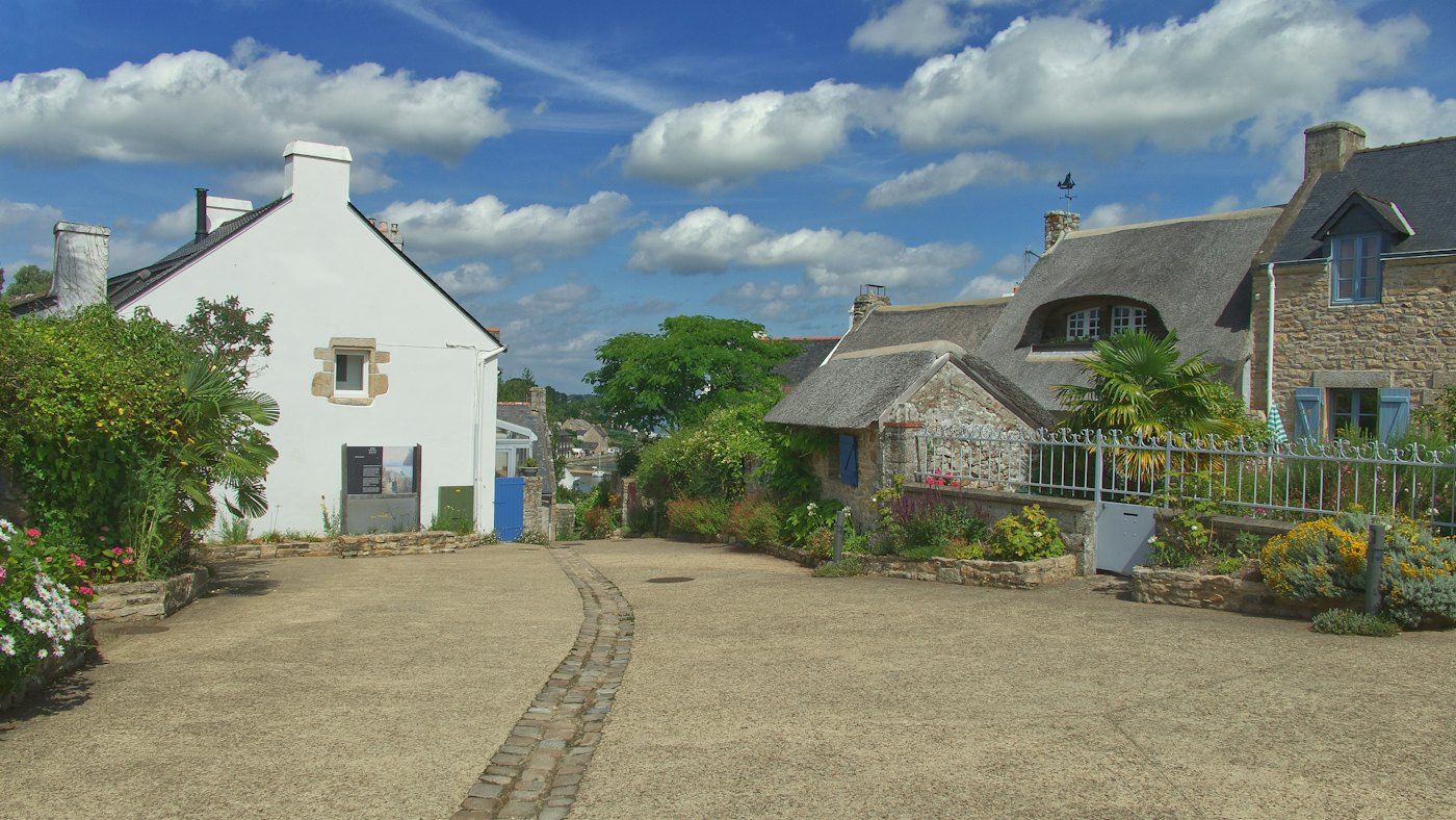 Neat little front gardens with flower beds and a white fence along a row of cottages